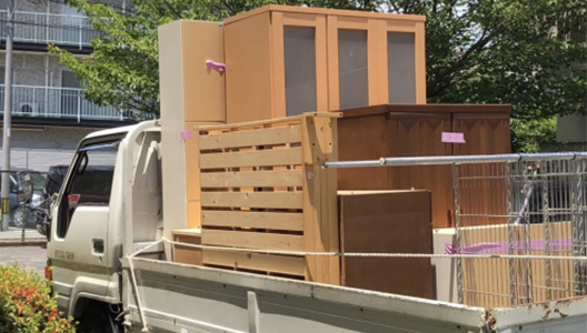 トラックの荷台に積み込まれた、大きなタンスや木製の棚などの大型家具